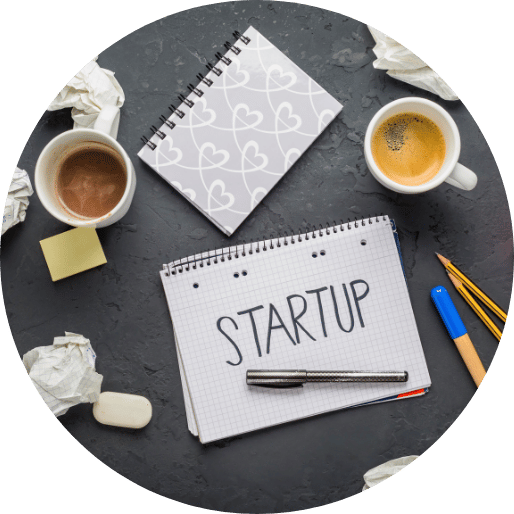 Startup written on notebook with office supplies and coffee on desk